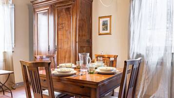 Een eettafel met stoelen, een karaf en borden gedekt voor een maaltijd.