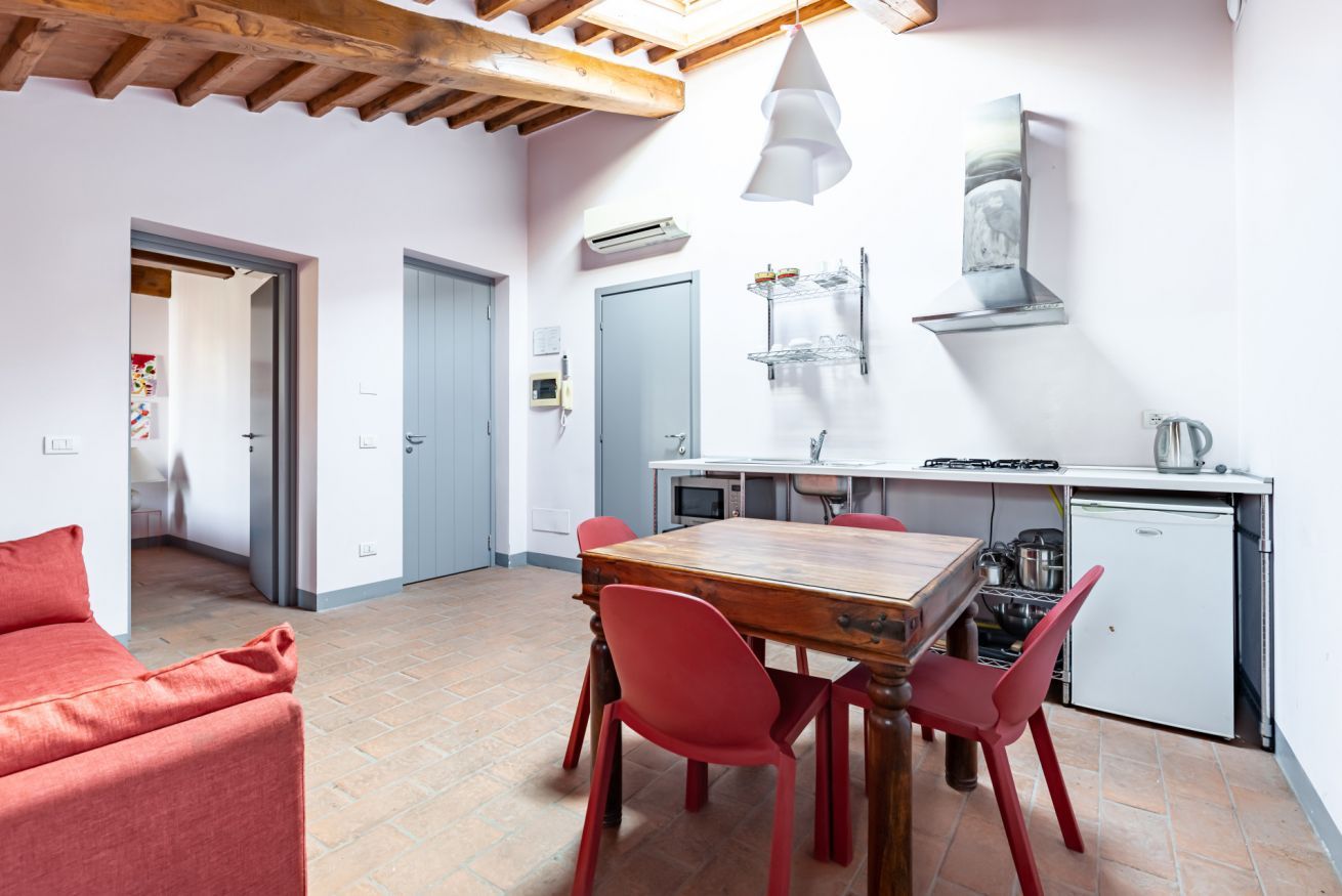 A compact kitchen with a dining table, chairs, and a small refrigerator.