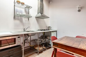 Una cocina compacta con microondas, estufa, fregadero y estanterías.