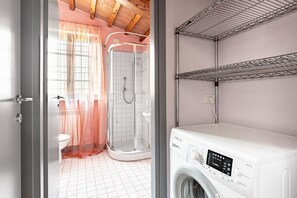 Un baño con ducha, inodoro y lavadora.