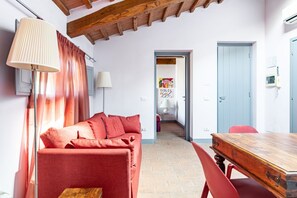 Una habitación acogedora con un sofá rojo, una mesa de madera y una lámpara.