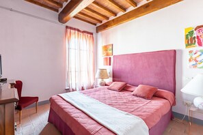 Un dormitorio con cama, escritorio, silla y ventana con cortinas.