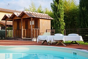 Una cabaña de madera con piscina, dos camas y una mesa con mantel blanco.