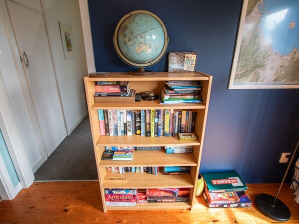 A bookshelf with various books and games, a globe, and a map on the wall.