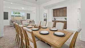 Un coin repas avec une table en bois dressée pour quatre personnes, entourée de chaises rembourrées.