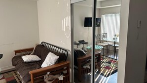 A modern living room with a sofa, a glass table, and a view into a dining area through a glass door. - Stylish 1BD Townhome. Dedicated Workspace, High-Speed Wi-Fi & Fast Transit (Toronto)