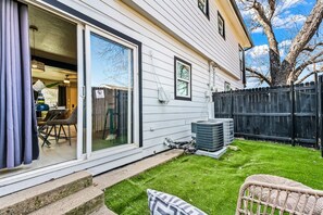 A residential property with a sliding glass door entrance, a fenced backyard, and outdoor furniture.