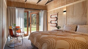 Une chambre avec un grand lit, une chaise, une table et une vue sur l’extérieur.