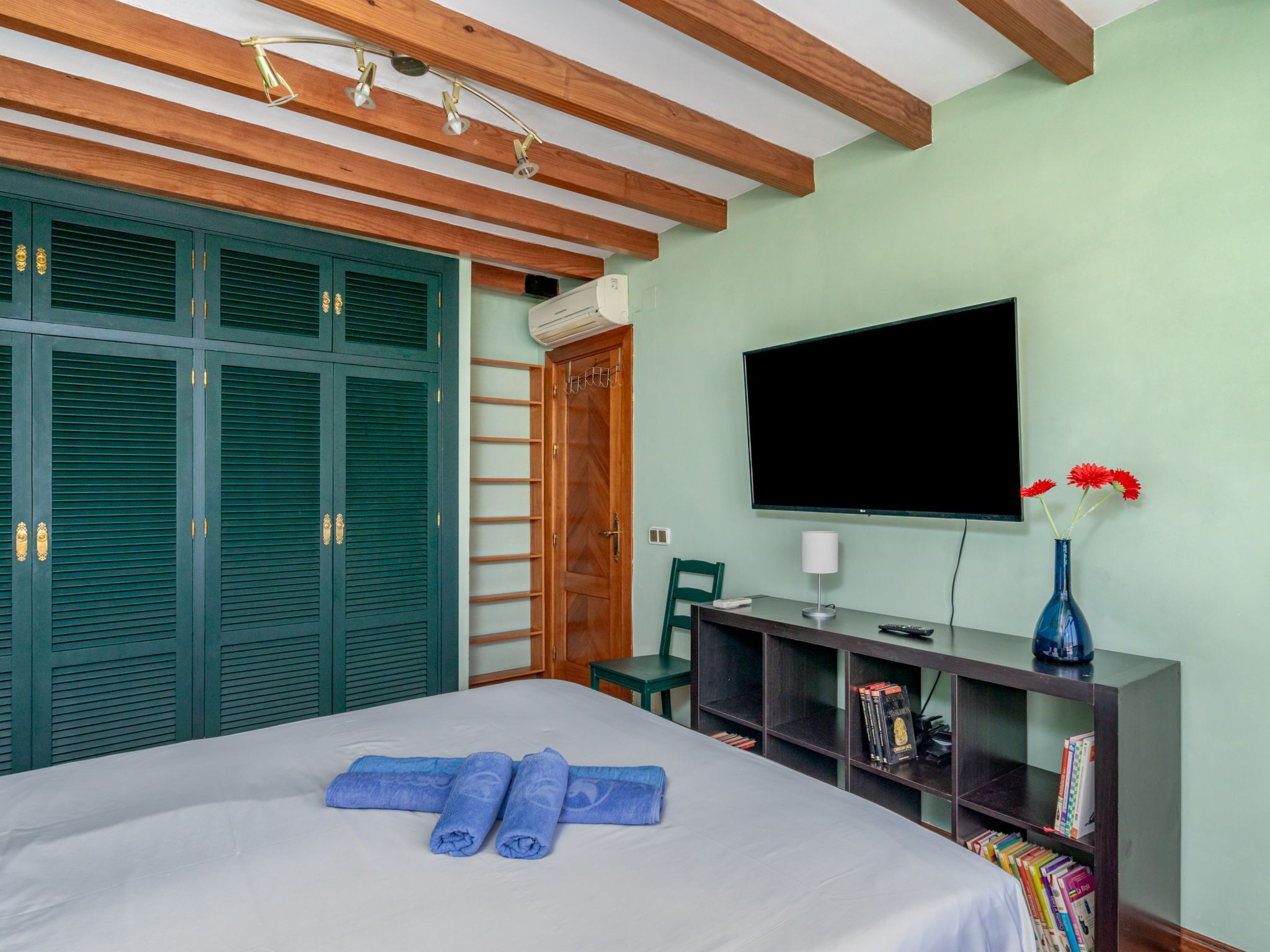 Quarto com cama, televisão, estante e guarda-roupa.