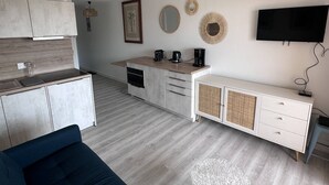 A modern kitchen with a built-in oven, a coffee maker, and a TV mounted on the wall.
