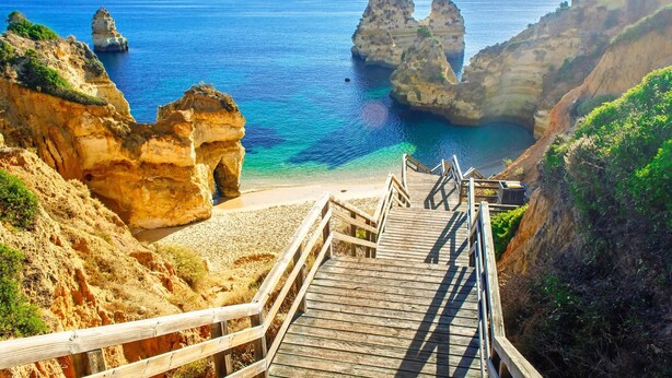 A wooden staircase leading to a beach with clear blue waters and rocky cliffs. - Historic Charm in the Heart of Lagos (Lagos)