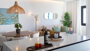 Une cuisine moderne avec un îlot central, un luminaire suspendu, un tableau au mur et une grande fenêtre.