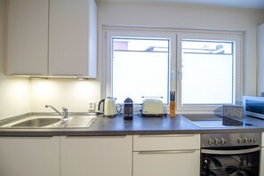 Una cocina con lavamanos, tostadora, hervidor y horno.