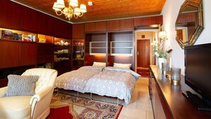 A bedroom with a large bed, a wooden ceiling, a bookshelf, and a TV. - Ostsee Lodge - Ostsee Lodge: Behaglich, Einzigartiger Meerblick & Perfekt zum Entspannen (Schashagen)