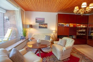 Una sala de estar acogedora con una mesa redonda, sillones de cuero, una estantería y vistas al exterior.