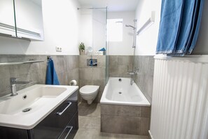 Ein modernes Badezimmer mit zwei Waschbecken, einer Toilette und einer Badewanne.
