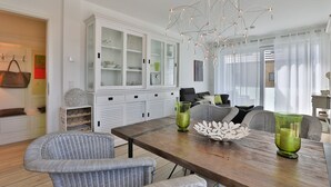 A dining area with a wooden table, wicker chairs, and a modern chandelier. - Ocean Breeze No.6 - Idealer Ostsee-urlaub: Neue Traumwohnung in Strandnähe (Timmendorfer Strand)