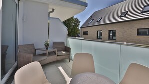 A balcony with wicker furniture, a glass table, and a potted plant. - Ocean Breeze No.6 - Idealer Ostsee-urlaub: Neue Traumwohnung in Strandnähe (Timmendorfer Strand)