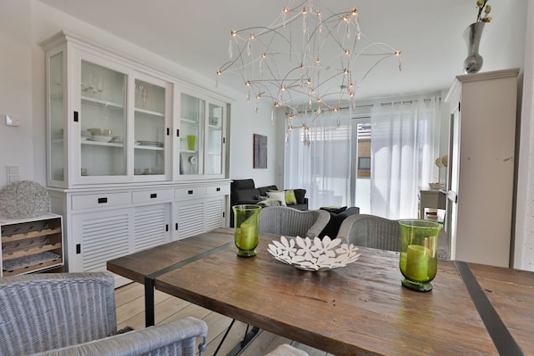 Un espace repas moderne avec une table en bois, deux vases en verre vert et un bol décoratif blanc.