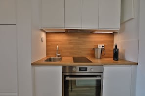A modern kitchen with a stainless steel sink, a built-in oven, and a wooden countertop.