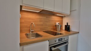 A modern kitchen with a stainless steel sink, wooden countertop, built-in oven, and white cabinetry. - Strandkoje No. 6 - Erstklassige Lage, Ausblick, Exklusive Ausstattung für Eine Entspannte Zeit (Timmendorfer Strand)