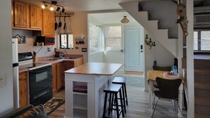 Una cocina con armarios de madera, estufa y comedor con taburetes.