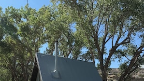 Un edificio de una planta con tejado inclinado, chimenea y antena parabólica.