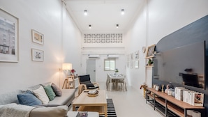 A modern living room with a sofa, coffee table, and a TV stand with books. - Roombix CityHouse -CozyHouse Near Bts for 12 ppl - RB4 (Krung Thep Maha Nakhon)