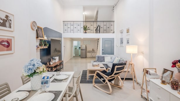 A modern, well-lit living room with a dining area, a staircase to an upper level, and a kitchen in the background. - Roombix CityHouse -CozyHouse Near Bts for 12 ppl - RB4 (Krung Thep Maha Nakhon)