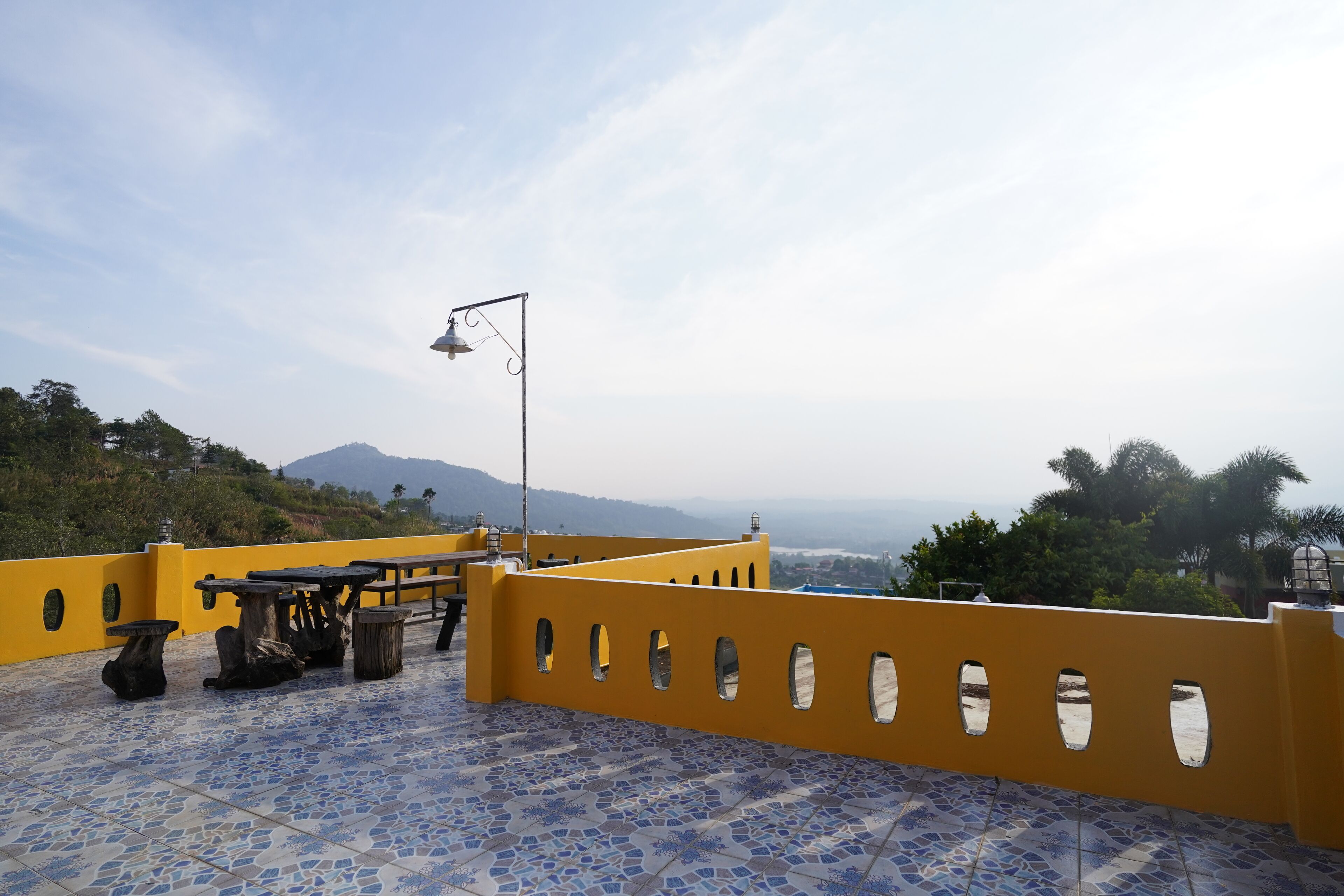 Una terraza con barandillas amarillas, una mesa y una lámpara.