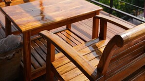 A wooden table and benches on a balcony with a view of a mountainous landscape.