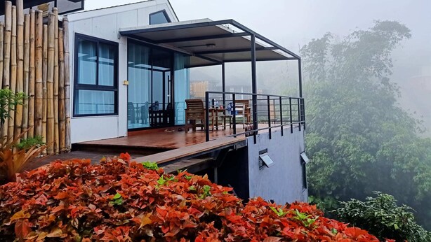 A modern building with a covered outdoor area, large windows, and a view of surrounding greenery. - Ban Rai Rabeangmok (Khao Kho)