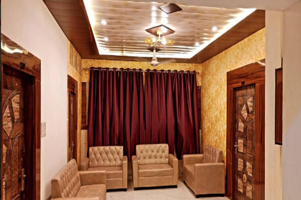Una habitación con ventilador de techo, dos sofás, una cortina roja y puertas de madera.