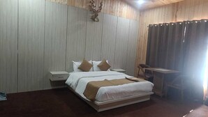 Un dormitorio con una cama, mesitas de noche, un escritorio y una decoración de cabeza de ciervo montada en la pared.