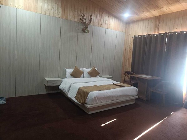 A bedroom with a bed, nightstands, a desk, and a wall-mounted deer head decoration. - Aranyam Hills (Lansdowne)