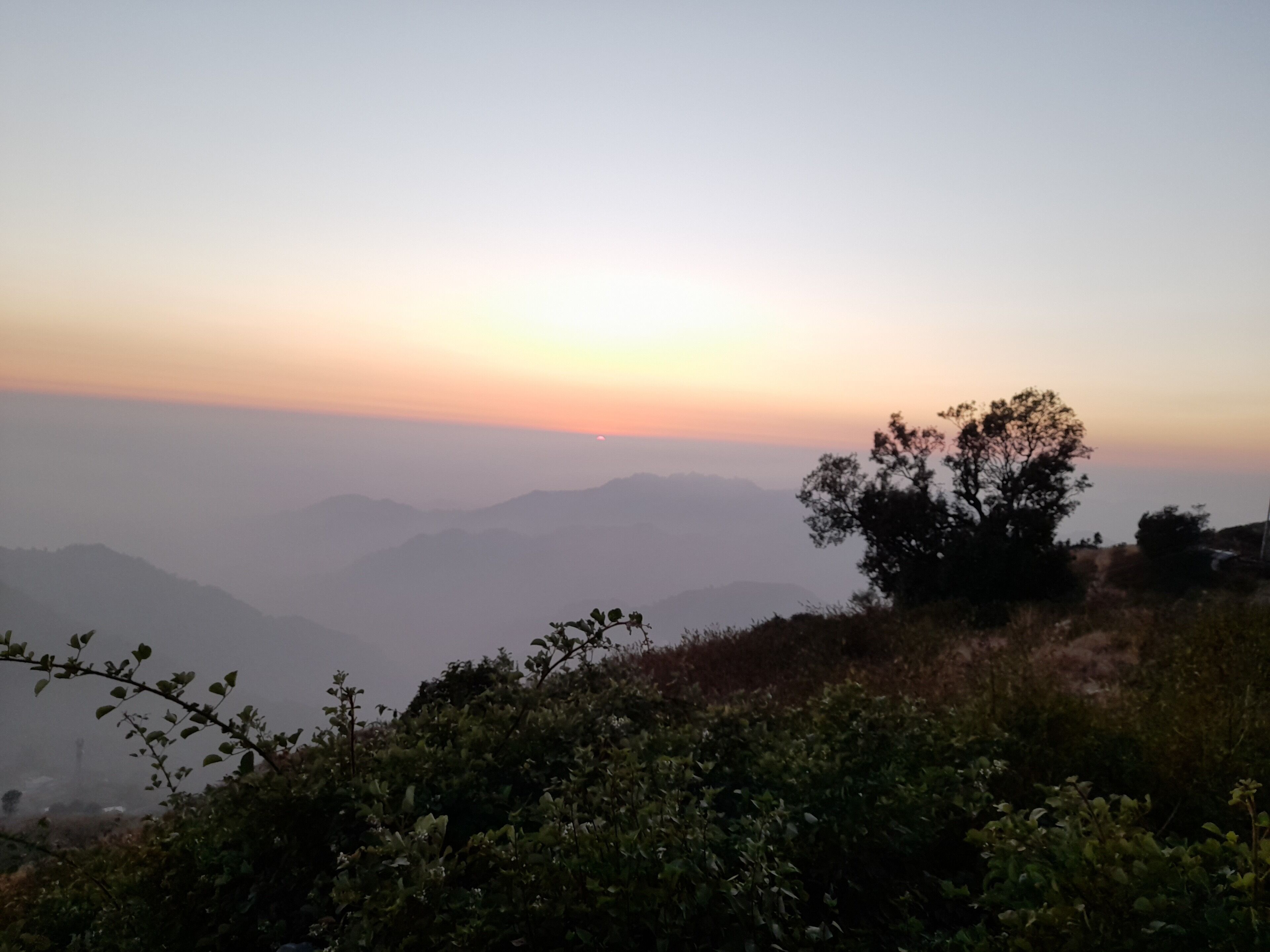 A view of a mountainous landscape with a sunset.