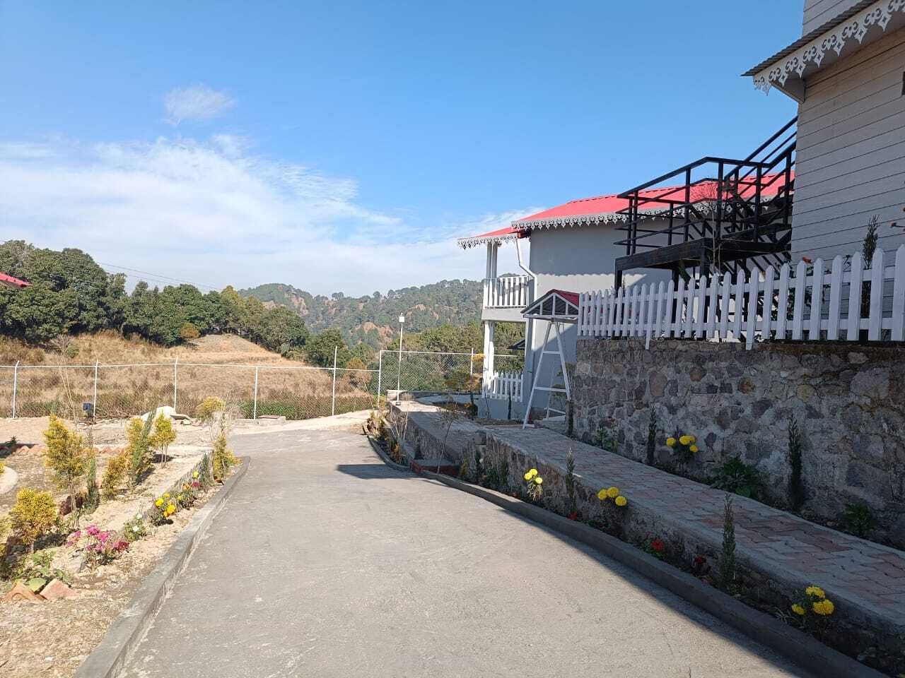 Un camino pavimentado que lleva a un edificio con cerca de piquetes blancos y techo rojo.