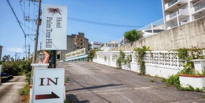 A sign for Hotel Palm Tree Hill with an arrow pointing right, indicating the direction to the hotel. - HOTEL Palm Tree Hill (Okinawa)