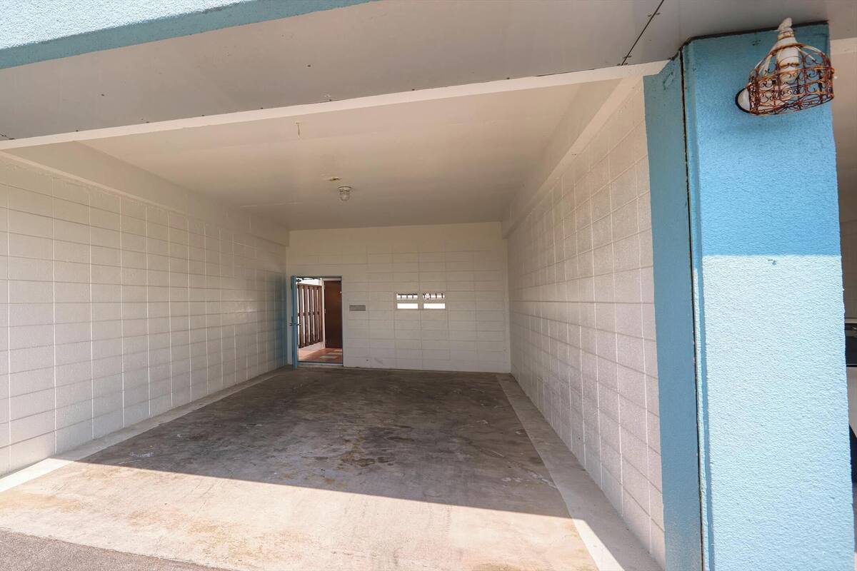 A covered parking area with tiled walls and a concrete floor.