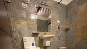 A bathroom with a toilet, sink, and shower area. - Lakefront Home Hotel (Ootacamund)