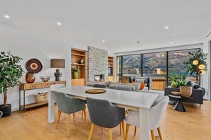 A modern living space with a dining area, seating, and a large window offering a mountain view. - Lakeview Luxury Vista 2-Bedroom (Wanaka)