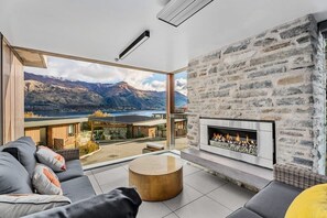 A modern living room with a stone fireplace, a large window offering a mountain view, and a cozy seating area.