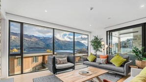 Un salon moderne doté de grandes fenêtres, d’un canapé, d’une table basse et d’un escalier menant à un espace extérieur.