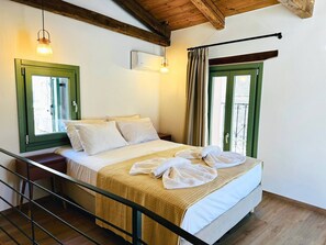 Habitación de hotel con cama, ventana con cortinas, techo de madera y unidad de aire acondicionado montada en la pared.