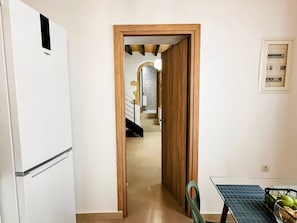 Um corredor que dá para uma escada, um refrigerador e uma mesa com um painel solar.