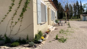 Un edificio con jardín, una pérgola y un cobertizo pequeño.
