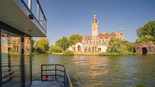 A river view from a boat with a historic building in the background. - Boat 'Hausboot Explorer' with Lake View and Private Terrace (Schwerin)