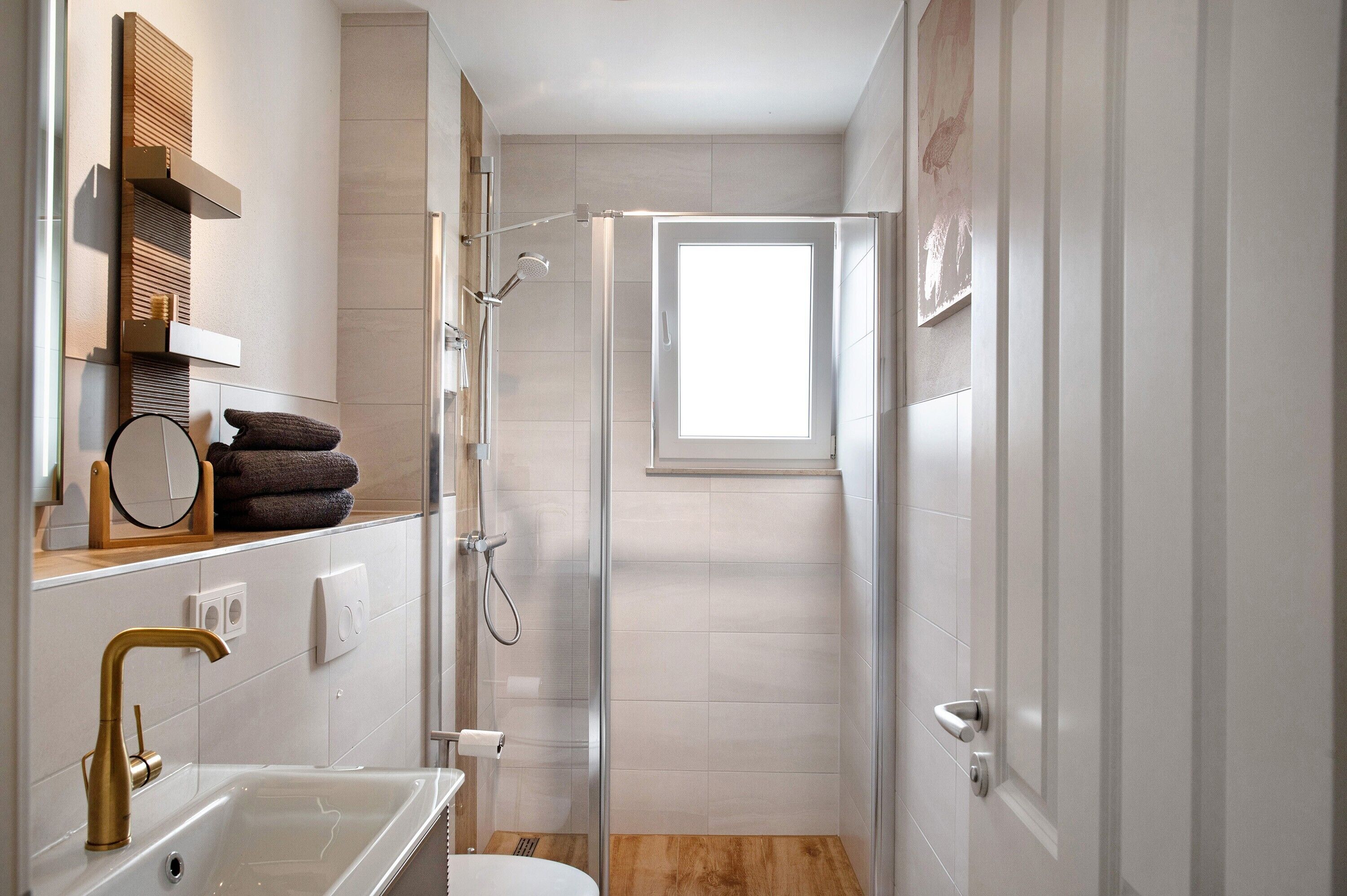 Ein modernes Badezimmer mit Dusche, Waschbecken, Spiegel und Fenster.