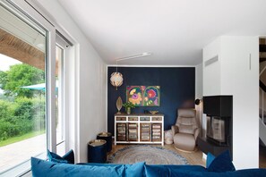 A modern living room with a sofa, a cabinet, a fireplace, and a large window.