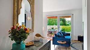 Un salón con un sofá azul, un espejo grande y un jarrón de flores.